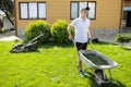 Man with a wheelbarrow of freshly cut grass. Person mows the lawn in the backyardÃÅ½ Royalty Free Stock Photo