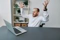 A man in a wheelchair businessman with tattoos in the office behind a laptop, anger and annoyance, hands up, the concept Royalty Free Stock Photo