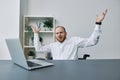 A man in a wheelchair businessman with tattoos in the office behind a laptop, anger and annoyance, hands up, the concept Royalty Free Stock Photo