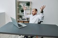 A man in a wheelchair businessman with tattoos in the office behind a laptop, anger and annoyance, hands up, the concept Royalty Free Stock Photo