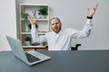 A man in a wheelchair businessman with tattoos in the office behind a laptop, anger and annoyance, hands up, the concept Royalty Free Stock Photo