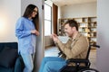 Man in wheelchair extend her hand palm up to side. Woman giving key with keychain from new house for handicapped Royalty Free Stock Photo