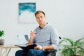 Man in wheelchair holding pen and notebook in living room Royalty Free Stock Photo