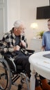 A woman from social care plays an elderly wheelchair user his favorite music. He rejoices and dances Royalty Free Stock Photo