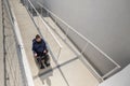 Man on wheelchair moving along an accessible ramp Royalty Free Stock Photo