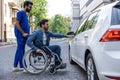 Man in a wheelchair opening a car door Royalty Free Stock Photo