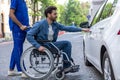 Man in a wheelchair opening a car door Royalty Free Stock Photo