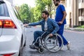 Man in a wheelchair opening a car door Royalty Free Stock Photo