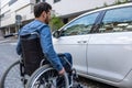Man in a wheelchair opening a car door Royalty Free Stock Photo