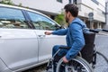 Man in a wheelchair opening a car door Royalty Free Stock Photo