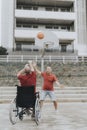 Man in a wheelchair plays basketball with his friends in a city park