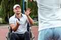 A man in a wheelchair plays basketball with his son on the sports ground. Disabled parent, happy childhood, disabled person