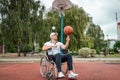 A man in a wheelchair plays basketball on the sports ground. The concept of a disabled person, a fulfilling life, a person with a