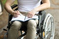 Man in wheelchair sits and holds notebook and pen. Royalty Free Stock Photo