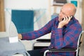 man on wheelchair talking by mobile phone