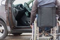 A man in a wheelchair trying to get into the driver`s seat of a car Royalty Free Stock Photo