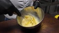 Female whisking chicken eggs in a metal bowl. Slow motion