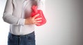 A man on a white background attaches a red heating pad with hot water to the elbow joint. Treatment of arthritis and