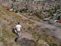 A man in white clothes walks down a mountain against the backdrop of destroyed slums in Ankara, Turkey. Young tourist with a Royalty Free Stock Photo