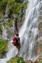 Man with white helmet on its red bacpack looking up at the Dalfazer Waterfall Dalfazer Wasserfall above Achensee, Austria Royalty Free Stock Photo