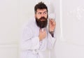 Man in white interior spying, eavesdropping. Secret and spy concept. Man with beard and mustache eavesdrops using mug Royalty Free Stock Photo
