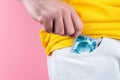 A man in white jeans pulls a condom out of his pocket. Hand close-up. Pink background. Concept of protection against sexually Royalty Free Stock Photo