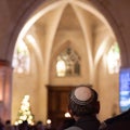 Man with a white kippah in a Synagogue with a blurry background and bokeh effect