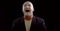 Man with white makeup on face is laughing like a joker in black background, evil uncontrollable laughter.