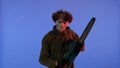 Man in white mask with chainsaw in hands on blue background with red neon light. Image of maniac Jason Voorhees from