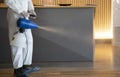 Man in white protective suit in the hotel or hospital sprays hotel rooms elevator to prevent the contamination of corona virus.