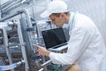 Man in a white robe with a laptop in his hands among the chrome pipes Royalty Free Stock Photo