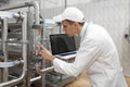 Man in a white robe with a laptop in his hands among the chrome pipes Royalty Free Stock Photo