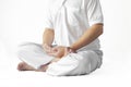 A man in a white robe meditating against a white backdrop with a clipping path