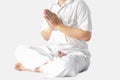 A man in a white robe meditating against a white backdrop with a clipping path