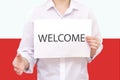 man with a white sheet of paper in his hands, with the inscription welcome. Against the background of the flag of Poland. Unknown Royalty Free Stock Photo