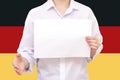 man with a white sheet of paper in his hands, for your text, mockup. Against the background of the flag of Germany. Unknown person Royalty Free Stock Photo