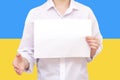 man with a white sheet of paper in his hands, for your text, mockup. Against the background of the flag of Ukraine. Unknown person Royalty Free Stock Photo