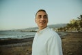 A man in a white shirt against the background of the sea and sunset. A guy is walking on the beach and enjoying the views, Royalty Free Stock Photo