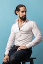 Man in white shirt and black trousers, sitting and looking away with confident expression. Royalty Free Stock Photo