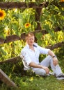 Man sits by fence near sunflowers Royalty Free Stock Photo