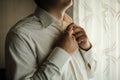 Man in white shirt, groom buttons his shirt, wedding day