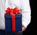 Man in a white shirt holds a blue gift cardboard box with a red bow Royalty Free Stock Photo