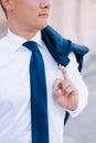 Man in a white shirt holds a jacket hanging on his shoulder with his finger Royalty Free Stock Photo