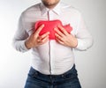 A man in a white shirt holds a red heating pad with hot water on his chest. Treatment of inflammation of the lungs and bronchitis