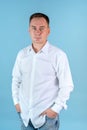 A man in a white shirt and jeans stands on a blue background with his hands in his pockets Royalty Free Stock Photo