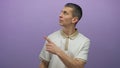 Man in white shirt looks up and points in front of purple wall background, isolated Royalty Free Stock Photo