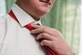 A man in a white shirt ties a red tie around his neck close up Royalty Free Stock Photo