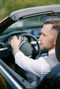 Man in a white shirt and vest sits at the wheel of a convertible. Back view. Close-up Royalty Free Stock Photo
