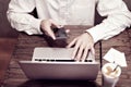 Man in white shirt working on portable computer and drinking latte in a cafe or coworking. Focus on guy`s hand and keyboard Royalty Free Stock Photo