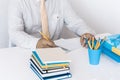 Man in white shirt and yellow tie making notes on modern stylish work place with office supplies, glasses, notebooks and books, Royalty Free Stock Photo